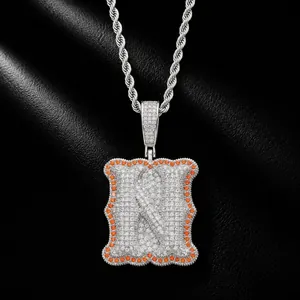 Detailed view of an iced-out letter N pendant with orange zircon border on a rope chain.