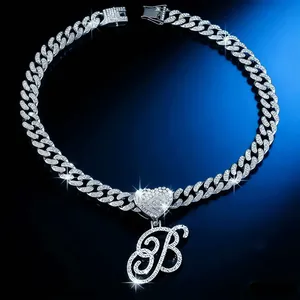 Close-up view of a sparkly iced-out Cuban link chain with heart and script letter B pendant