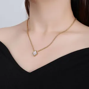 Detail shot of a stainless steel necklace with a square mother of pearl pendant on model