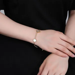Close-up of elegant gold titanium steel bracelet featuring square white shell pendants on wrist