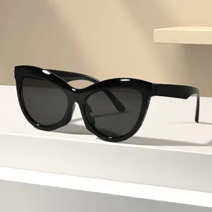 Lunettes de soleil œil-de-chat rétro avec monture noire brillante et verres foncés chic.