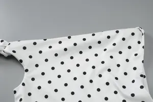 Detailaufnahme des hochwertigen weißen Stoffes mit schwarzen Punkten am schicken Kleiddetail