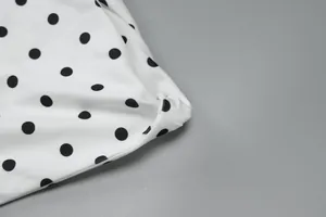 Nahaufnahme eines eleganten weißen Stoffes mit schwarzen Punkten und stilvollem Knotendetail.
