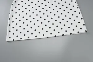 Detailaufnahme des Saums eines weißen Kleides mit klassischem schwarzem Polka-Dot-Muster