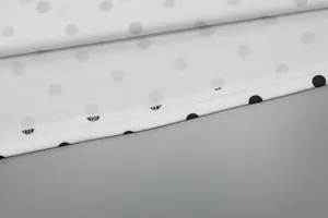 Detailaufnahme des weißen Kleidersaums mit schwarzen Punkten und sauberen Nähten