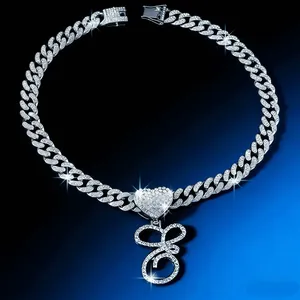 Close-up of iced out Cuban link chain with heart connector and script letter G pendant