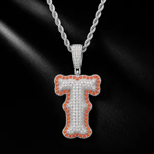 Close-up of iced-out bubble letter T pendant with orange and white CZ stones on a silver rope chain
