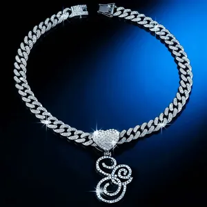 Detailed view of iced out Cuban link necklace with heart and cursive letter E pendant.