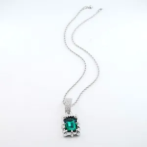 Close-up of elegant silver necklace featuring a rectangular green emerald gemstone pendant