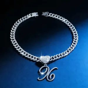 Detail shot of iced out cuban link necklace featuring a heart and cursive K pendant