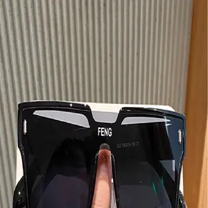 Primer plano de gafas de sol cuadradas negras extragrandes con logo FENG de moda en el puente.
