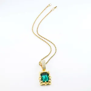 Detail of vintage gold rope chain necklace with a large emerald green gemstone pendant.