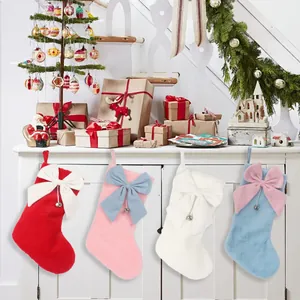 Detailansicht von vier farbenfrohen Plüsch-Weihnachtssocken mit dekorativen Schleifen und Glocken
