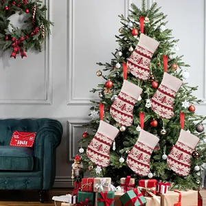 Set of six mini knitted Christmas stockings hanging as festive ornaments on a tree.
