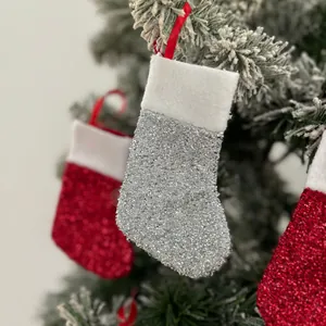 Macro view of mini silver glitter Christmas stocking hanging on a snowy pine tree branch