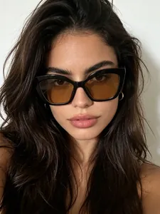 Close-up view of stylish black cat-eye sunglasses with brown tinted lenses on model