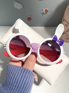Detailed view of white bunny shaped children's sunglasses with purple bow and gradient lenses
