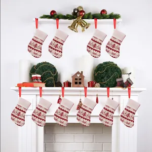 Detailed view of mini red and white knitted Christmas stockings hanging on a white fireplace
