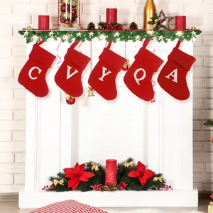 Feestelijke rode gebreide kerstsokken met witte letters hangend aan een witte open haard
