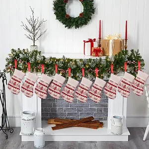 Set of 10 mini knitted Christmas stockings hanging on fireplace with snowflake pattern