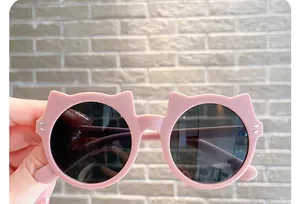 Close-up detail of cute cat-ear shaped children's sunglasses with stylish mauve pink frames.