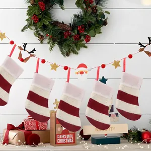 Detail of red and white striped knitted Christmas stockings in a festive scene setting.