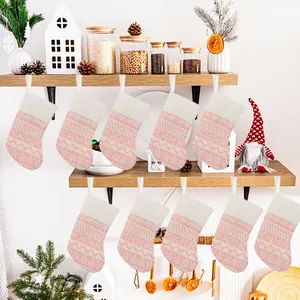Set of 10 pink knitted Christmas stockings hung on a rustic shelf for holiday decor.