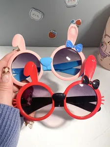 Close-up of cute pink and red cartoon rabbit-shaped sunglasses with ears and bows for kids