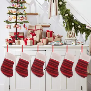 Red and dark red striped knitted Christmas stockings hanging on a white cabinet