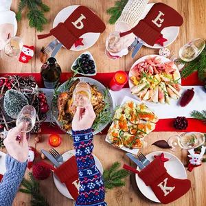 Feestelijke rode gebreide kerstsokken als bestekhouder op een mooi versierde tafel.