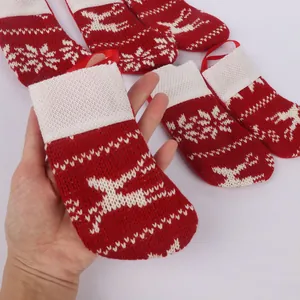 Miniature red knitted Christmas stocking with reindeer pattern held in hand