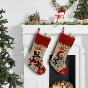 Festliche Weihnachtssocken aus Jute mit Weihnachtsmann am weißen Kaminsims aufgehängt