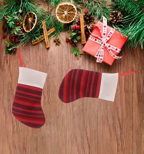 Mini knitted Christmas stockings with red stripes on a festive wooden background.