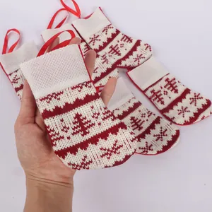 Close-up of a hand holding a mini red and white knitted Christmas stocking for holiday decor