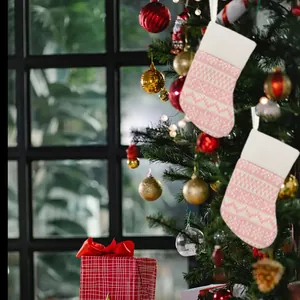 Close-up view of pink knitted Christmas stockings hanging on a festive decorated tree.