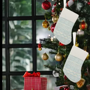 Detail view of light blue knitted Christmas stockings hanging on a festive tree.