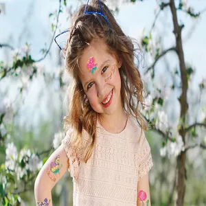 Detailansicht eines lächelnden Kindes mit süßen Goldfolien-Schmetterling-Tattoos.