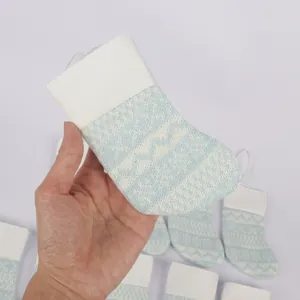 Detailed view of hand holding a small light blue and white knitted Christmas stocking