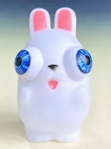 Detailansicht eines weißen Kaninchen-Quetschspielzeugs mit blauen hervorstehenden Augen.