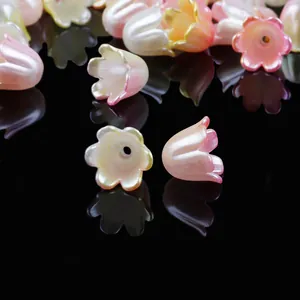 Primer plano de cuentas de lirio de los valles con pétalos degradados rosa y blanco.