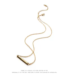 Detalle de un collar de barra dorada minimalista con coordenadas geográficas grabadas