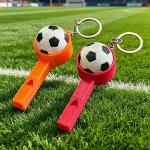 Detailansicht von 3D-gedruckten Fußballpfeifen-Schlüsselanhängern auf grünem Rasen