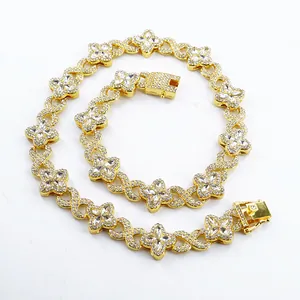 Detailed view of iced-out gold-tone four-leaf clover and infinity link Cuban chain necklace