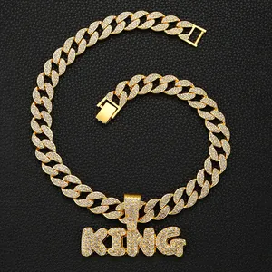 Gros plan sur un collier gourmette doré avec pendentif lettres KING scintillantes