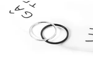 Nahaufnahme von silbernen und schwarzen minimalistischen dünnen Ringen auf Teller