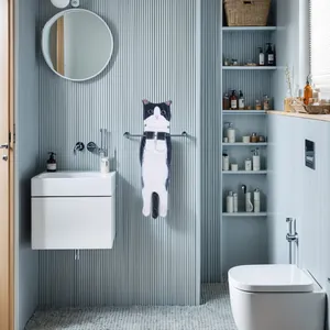 Cute black and white cat-shaped hanging hand towel displayed in a modern bathroom detail.