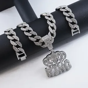 Detailed view of iced out KING crown pendant on a sparkling silver Cuban link chain