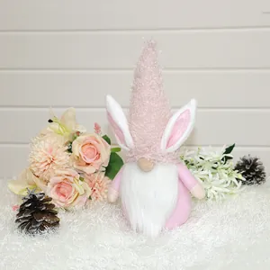 Een pluchen roze paaskabouter met konijnenoren omringd door decoratieve rozen.