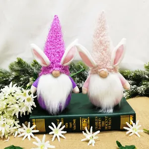 Twee kleurrijke paaskabouter pluchen poppen met konijnenoren op een decoratief boek