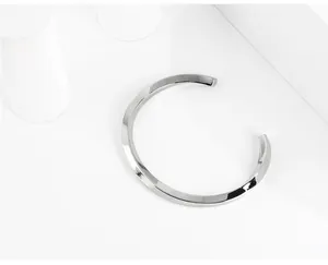 Brazalete de acero de titanio plateado pulido de alta calidad en fondo blanco minimalista